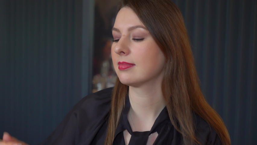 A young woman eating soup with a spoon. A girl in a restaurant or cafe eats lunch or dinner indoors. Vegetable Italian minestrone soup, green. Tasty meal in Italy. Female takes spoon from napkin.