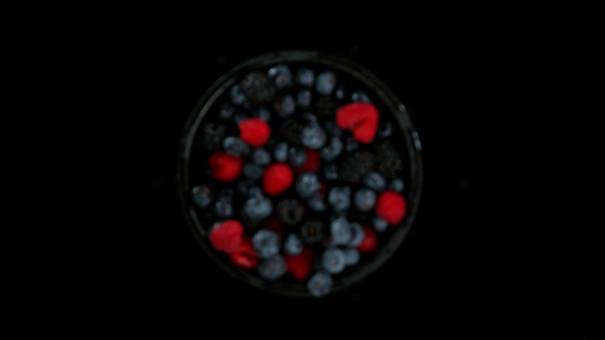 Super slow motion shot of rotating exploded berries fruit with splashing water on black at 1000fps. Royalty-Free Stock Footage #1088058505