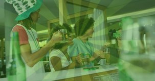 Animation of green lines over happy diverse friends wearing clover shape items and drinking beer. social media and st patrick's day celebration concept digitally generated video.