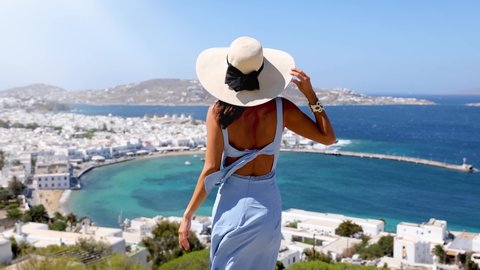 Attractive woman with blue dress enjoys the view over the town of Mykonos, Greece