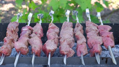 Kebab cooking outdoors on metal skewer. Traditional eastern dish - Marinated barbecue meat cooked at barbeque. Grilled pork, meat lamb, shish kebabs, shashlik. Street food, grill on charcoal and flame