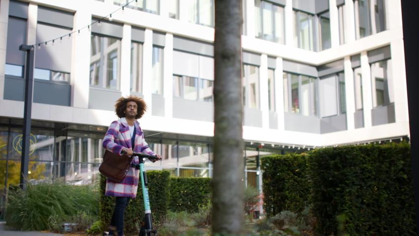 Cool multiracial mid audlt man riding electric scooter in street