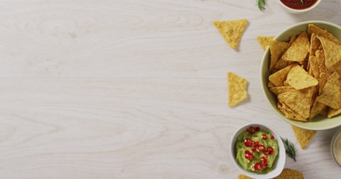 Video of tortilla chips, guacamole and salsa dip on a wooden surface. party food and savoury snacks.