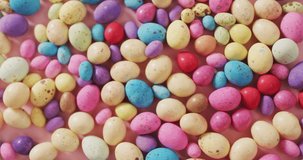 Video of decorated colorful easter eggs on a pink surface. seasonal easter traditional sweet treats.