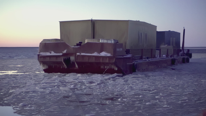 Large barge at the North Pole. CLIP. In the foreground is a man in defocus. In the background, in focus, a heavy barge in the water with ice