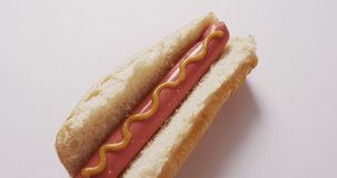 Video of hot dog with mustard on a white surface. food, cuisine and catering ingredients.