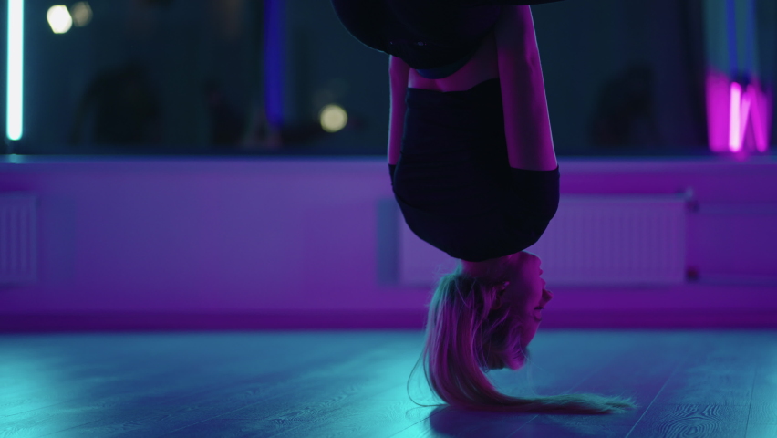 Woman hanging upside down and using yoga hammock swing while doing antigravity yoga exercise. Back view of beautiful young woman using hammock for doing pose of antigravity yoga