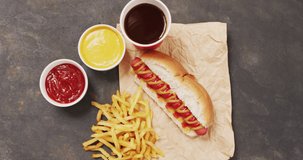 Video of hot dog with mustard, ketchup and chips on a black surface. food, cuisine and catering ingredients.