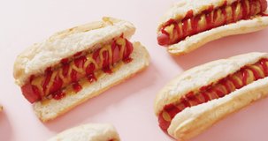 Video of hot dogs with mustard and ketchup on a pink surface. food, cuisine and catering ingredients.