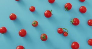 Video of fresh cherry tomatoes on blue background. fusion food, fresh vegetables and healthy eating concept.
