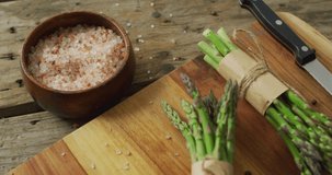 Video of two fresh asparagus bundles on wooden chopping board. fusion food, fresh vegetables and healthy eating concept.