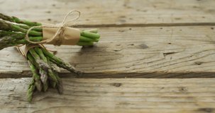 Video of two fresh asparagus bundles on wooden background. fusion food, fresh vegetables and healthy eating concept.
