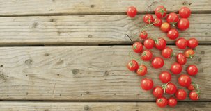 Video of fresh cherry tomatoes with copy space on wooden background. fusion food, fresh vegetables and healthy eating concept.
