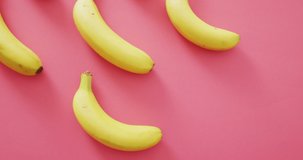 Video of fresh bananas with copy space on pink background. fusion food, fresh fruit and healthy eating concept.