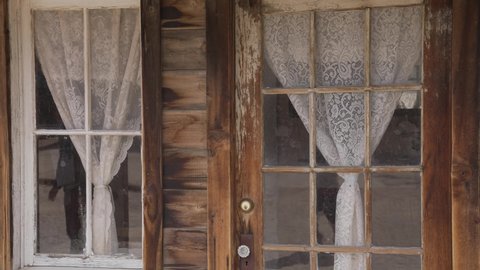 This panning vide shows the front of an old western building with victorian lace curtains in the windows.