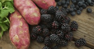 Video of fresh berries and sweet potatoes over wooden background. fusion food, fresh vegetables and healthy eating concept.