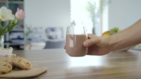 Hand taking glass of chocolate milk to drink