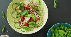 Video of fresh salad with green leaves and bowls with salad leaves and nuts on grey background. fusion food, fresh vegetables and healthy eating concept.