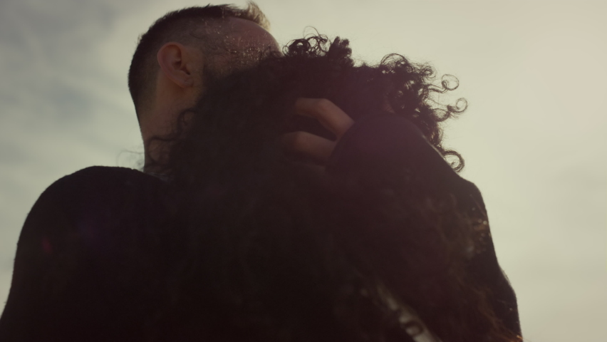 Romantic couple cuddling outdoors. Two lovers touch curly hair at sunset sky. Unknown relationship people hugging together on sunny day close up. Peaceful romantic partners enjoy peace. Love concept.