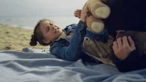 Small kid play parents on sea beach. Happy family spend time together at seashore. Cute little girl holding teddy bear on nature outside close up. Playful people enjoy summer vacation. Holiday concept - Powered by Shutterstock - Get 15% off with code: PIKWIZARD15