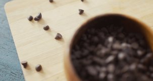 Video of close up of bowl with organic chocolate chip on wooden background. fusion food, organic ingredients and healthy eating concept.
