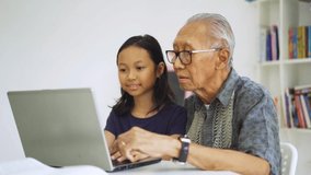 Video footage of senior man and his granddaughter using a laptop computer together in the library - Powered by Shutterstock - Get 15% off with code: PIKWIZARD15