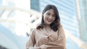 Teenager Asian woman feeling happy smiling and looking to camera while relax at outdoor city space. Portrait of successful business woman applause the hand to the camera. Happy feeling concept