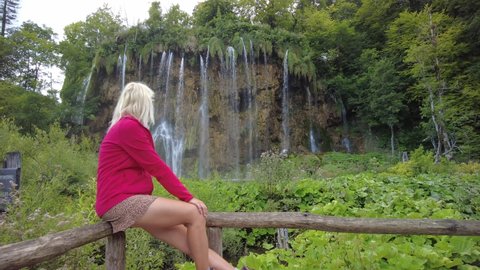 Woman under the Veliki prstavac waterfall of Plitvice Lakes National Park in Croatia in the Lika region. UNESCO World Heritage of Croatia named Plitvicka Jezera.