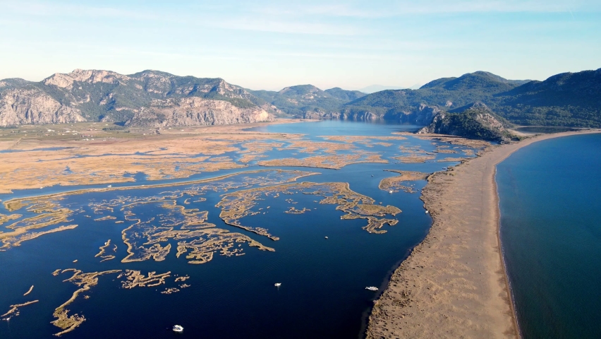 A shining summer sun and people sunbathing on the beach while enjoying the boat at Muğla Iztuzu Beach, one of Turkey