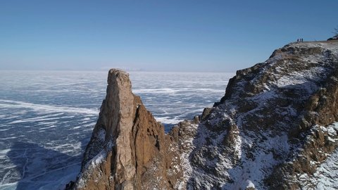 Aerial orbital shot of cape Khoboy, Olkhon island. Tall rocks in frozen lake Baikal. Popular touristic destination. Winter landscape. Panoramic view