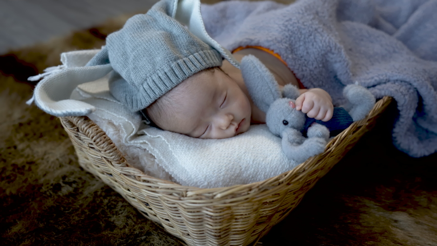 4k, Cute Asian newborn baby. wearing a blue rabbit Sleep well. By hugging the rabbit doll. lying in a wicker basket	