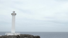 YOMITANSON, OKINAWA, JAPAN - AUG 2021 : View of lighthouse at Zanpa Misaki (Cape Zanpa) and East China Sea (Ocean). Wide view, time lapse shot in day. Summer holiday, vacation and resort concept video