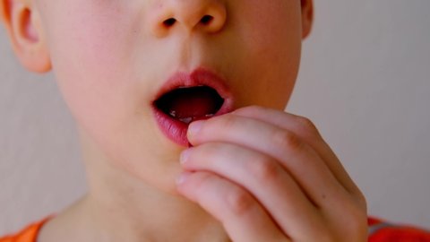 close-up of part of child's face, child, boy 8-10 years old holds in hand, wants to eat gelatinous sweets, gummy bear, concept of children's delicacy, healthy and unhealthy food, halal food