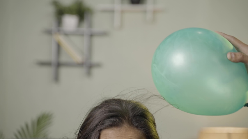 close up shoto of kids playing by placing balloon to attracting hair - conept of static cling home science experiment and learning. Royalty-Free Stock Footage #1088086319