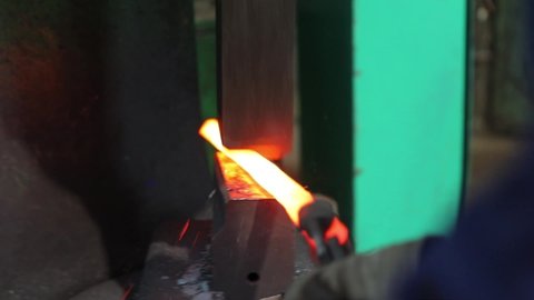 Blacksmith forges hot metal, iron in smithy. Blacksmith uses his tools.