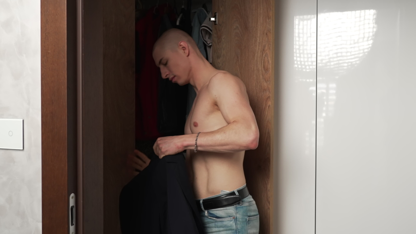 Fashionable bare chested caucasian gay man putting on a black blazer, preparing for a night out. High quality 4k footage