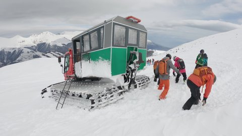 Popova Sapka, Macedonia - 11 Jan, 2022: Freestyle skiers are transported on the mountain peak by snowplow ratrack for offpiste extreme skiing, slow motion