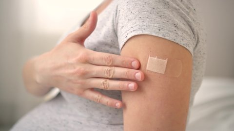 Vaccination of a pregnant woman. Close view of shoulder after vaccine injection with adhesive tape. Covid vaccination concept. Health and medicine during pregnancy.