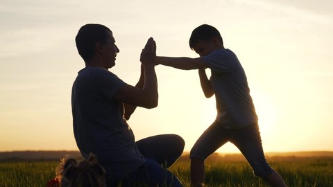 father and son boxing box silhouette fun at sunset. happy family in the park play sport concept. father and son training fight silhouette in the park. happy family together teamwork training