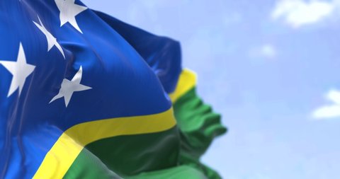 Detail of the national flag of Solomon Islands waving in the wind on a clear day. Solomon Islands is a sovereign country in Oceania. Selective focus. Seamless loop in slow motion