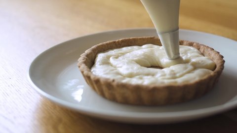 a female chef is piping custard onto a pie
