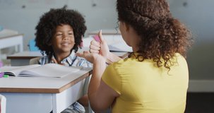 Video of happy caucasian female teacher learning math to african american boy. primary school education and teaching profession.
