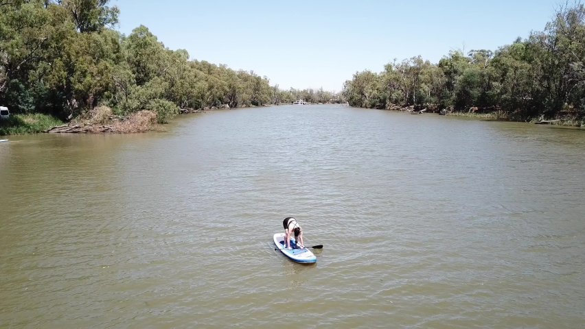 Drone aerial over river woman standing up on stand up paddle board