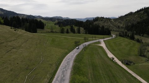 VW van driving in alone road, sunny, drone shot. Van life trip. Areal view on nature. 