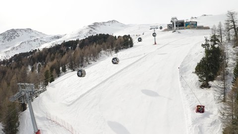 Livigno, Italy - February 21, 2022: aerial view of Livigno ski resort in Lombardy, Italy. Chairlifts, ski lifts, gondola cabin are moving and skiers skiing over scenery panorama. 4k video footage 