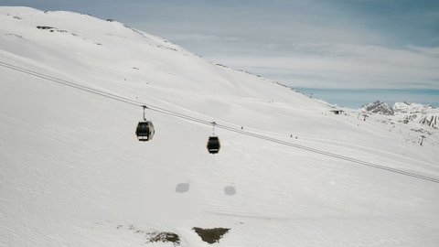 Livigno, Italy - February 21, 2022: aerial view of Livigno ski resort in Lombardy, Italy. Chairlifts, ski lifts are going up and down, skiers skiing at the background. 4k video footage 