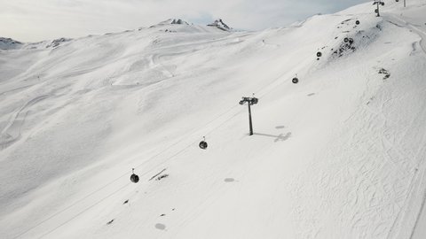 Livigno, Italy - February 21, 2022: aerial view of Livigno ski resort in Lombardy, Italy. Chairlifts, ski lifts are going up and down, skiers skiing at the background. 4k video footage