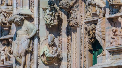 Decoration at the Gothic Cathedral of Milan. Statues and bas-reliefs. Piazza del Duomo before sunset. Blue sky over the temple. Architettura and details closeup. Sculptures, statues style in details