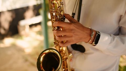 Saxophonist in white shirt play on golden saxophone. Live performance. Jazz music. Musician playing in jazz band. Hands musician close up day outdoors. Saxophonist, Saxophones player