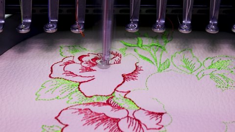 Machine embroidery on beige leather with red and green thread. Embroidery design with flowers up close. 4k video